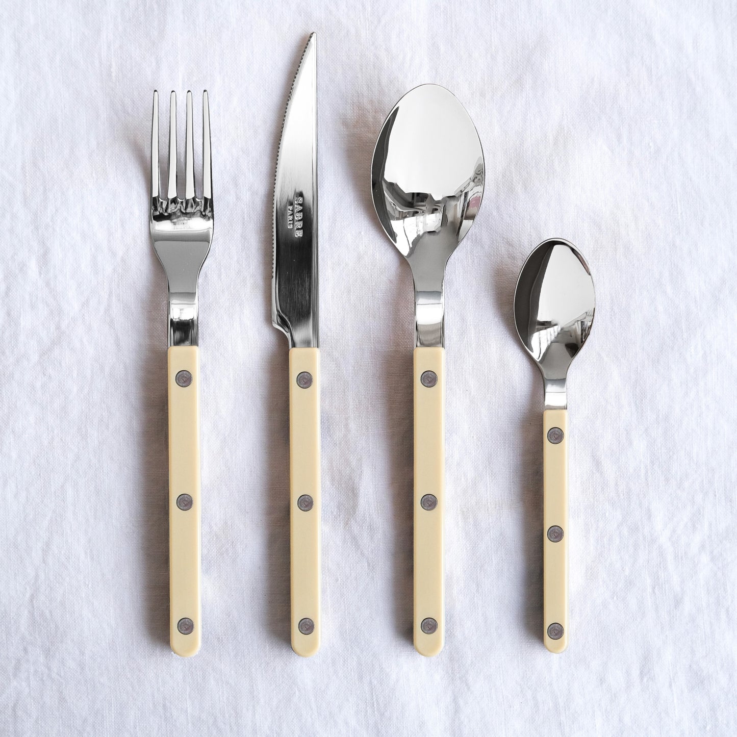 Set of silver cutlery with beige handles on a white background